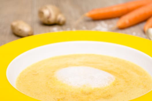 Foam of coconut milk on soup with carrots in a plate