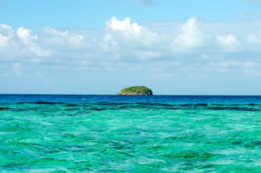 Small green island on the horizon of the Caribbean Sea near San Andres y Providencia, Colombia
