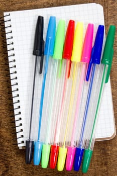 Colorful pens and spiral notebook on the wooden desk