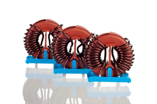 Three toroidal chokes insulated and mirrored on a white background