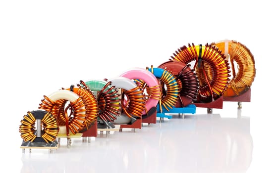 Selection of different toroidal chokes diagonally in a row isolated against a white background