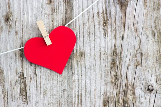 red heart hanging on line against old wood-grain wall
