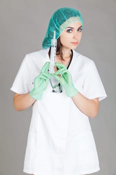 Young female doctor with syringe.  Doctor with syringe on grey background