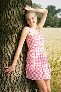 Young woman leaning against a tree