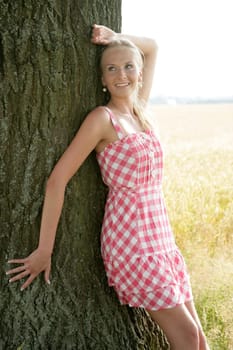 Young woman leaning against a tree