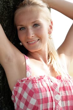 Young woman leaning against a tree