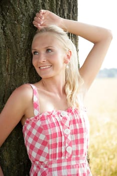 Young woman leaning against a tree