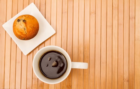 Vanilla with chocolate chips Muffins on a white plate with  a cup of coffee.
