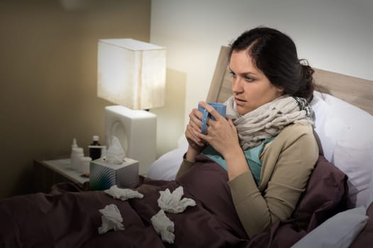 Caucasian woman sitting in bed having bad cold