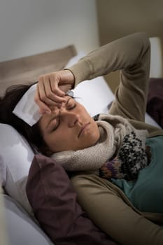 Young ill woman in bed having high fever flu
