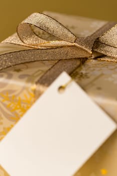Christmas gift with blank tag focus on gold ribbon