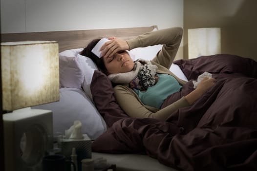 Young Caucasian woman lying sick in bed suffering from cold
