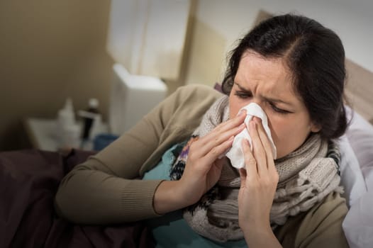 Caucasian woman having bad cold blowing her nose