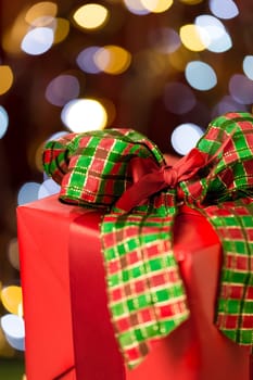 Traditional red christmas present with bow on shining lights background