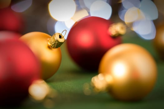 Gold and red christmas baubles on green lights background