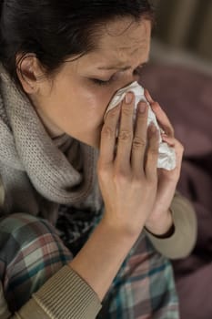 Close up portrait of woman sneezing into tissue