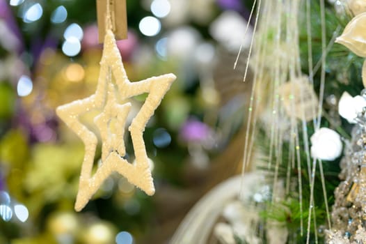 Sparkling gold star ornament hanging from Christmas tree