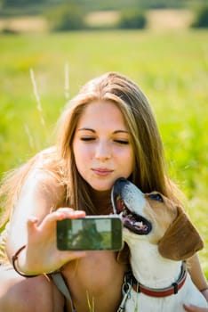 Teen girl taking photo of herself and her dog with mobile phone camera
