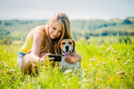 Young woman taking photo of herself and her pet with mobile phone camera
