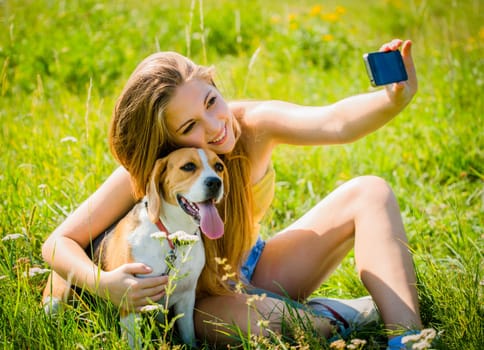 Teen girl taking photo of herself and her dog with mobile phone camera