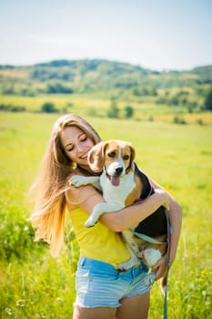 Teen girl holding her pet (beagle dog) - outdoor in nature