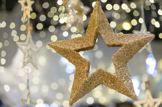 Hanging golden star Christmas decoration on blurred background