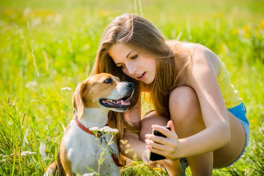 Teen girl showing something to her dog on smart-phone, outdoor in nature