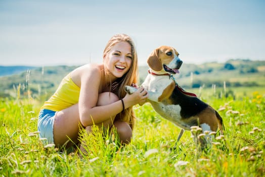 Lifestyle photo of happy young girl with her pet (beagle dog) - outdoor in nature