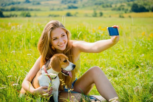 Young woman taking photo of herself and her pet with mobile phone camera