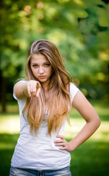 Cheeky teen girl showing to the front with finger - outdoor in nature