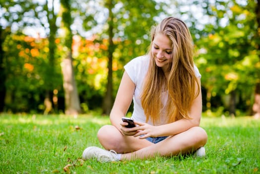 Young beautiful woman (teen girl) with smartphone - lifestyle outdoor in park