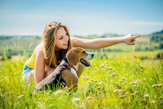 Young woman (teen girl) showing her dog with hand - outdoor in nature