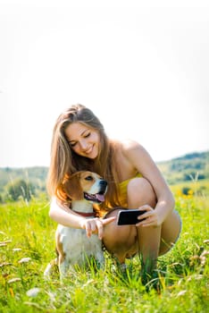 Teen girl showing something to her dog on smart-phone, outdoor in nature