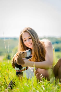 Lifestyle photo of happy young girl with her pet (beagle dog) - outdoor in nature