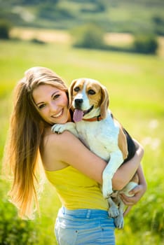 Portrait of young woman with her pet (beagle dog) - outside in nature