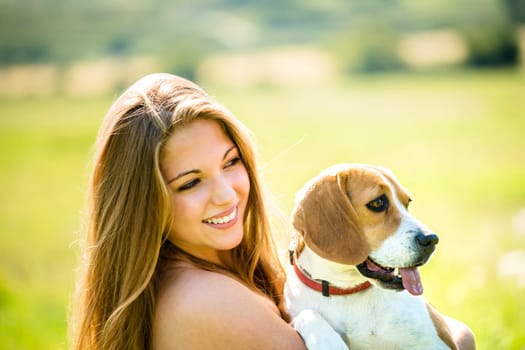 Teen girl holding her pet (beagle dog) - outdoor in nature