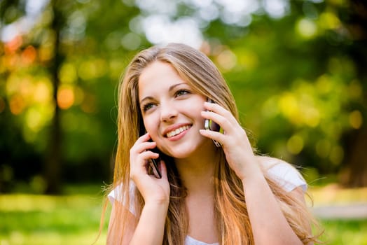 Teen girl calling with 2 mobile phones outdoor - mobility concept