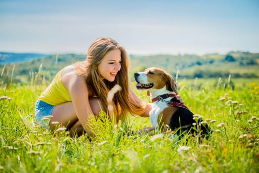 Lifestyle photo of happy young girl with her pet (beagle dog) - outdoor in nature