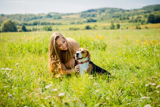Lifestyle photo of happy young girl with her pet (beagle dog) - outdoor in nature
