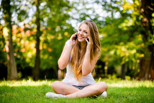 Tecnology in excess - teen girl calling with 2 mobile phones outdoor