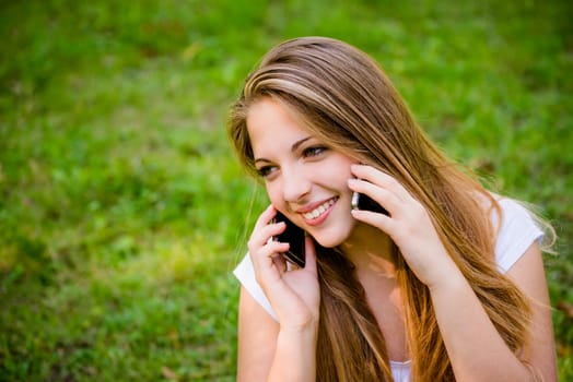 Tecnology in excess - teen girl calling with 2 mobile phones outdoor