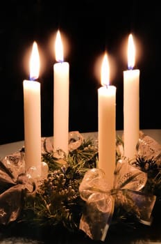 Christmas advent wreath with burning candles laid on table with black background