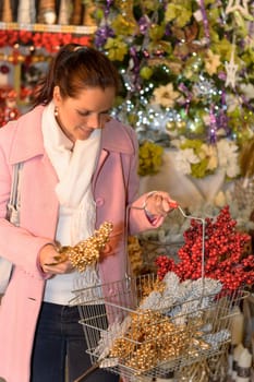 Smiling woman putting Xmas decorations to shopping basket