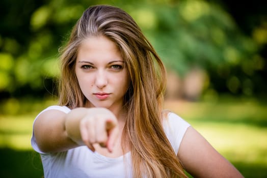 Cheeky teen girl showing to the front with finger - outdoor in nature