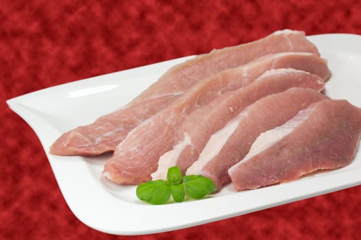 Sliced ​​pork on a white plate. Red background.