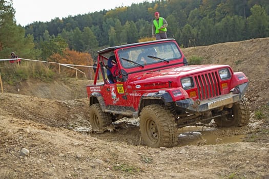 MOHELNICE, CZECH REPUBLIC - OCT 05. Red car is passing through  a puddle of mud on a trial race in the "BIG SHOCK CUP Trial 2013"" on October 05, 2013 in Mohelnice, Czech Republic."