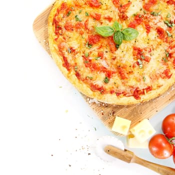 Top view of a pizza Margherita surrounded by ingredients and kitchen tools