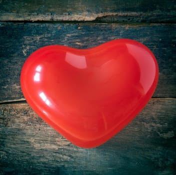 Red romantic Valentines or Christmas heart for sending special festive greetings to a sweetheart or loved one on a textured wooden background