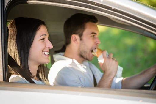 Couple in car - man driving and eating