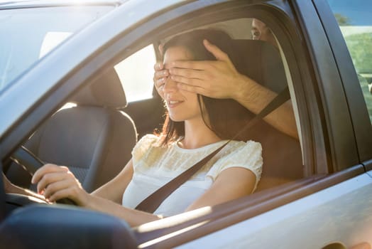 Young couple in car - man covering eyes of his girlfriend